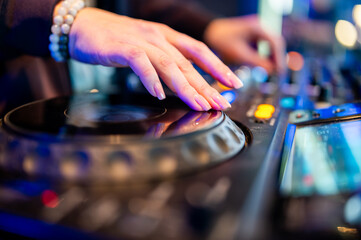 DJ’s hands skillfully manipulating a music mixer, capturing the energetic atmosphere of a live performance