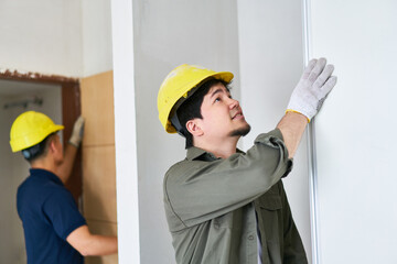Young male carpenters wearing safety workwear installing doors at incomplete house