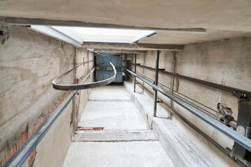 Directly below view of illuminated elevator shaft inside incomplete building at construction site