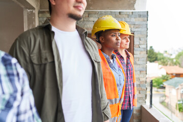 Diverse construction coworkers looking out from incomplete house