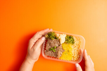 Hands serving packed lunch box home prepared meal in aerial top view close up empty space isolated
