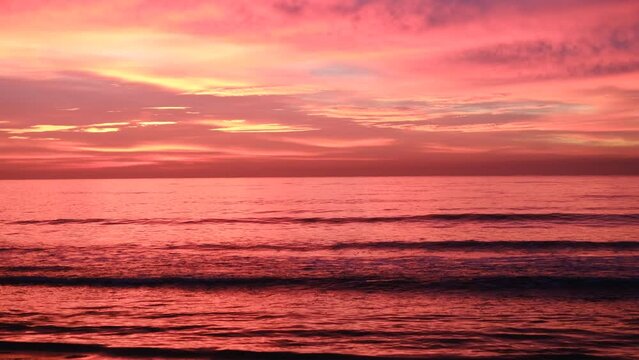 Video en 4K del mar al amanecer con el cielo rojo y naranja.