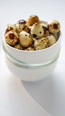 quail eggs in ceramic bowl over white background