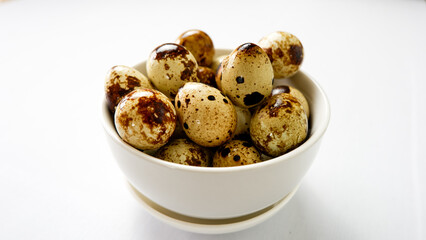 quail eggs in ceramic bowl over white background