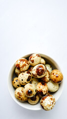 quail eggs in ceramic bowl over white background