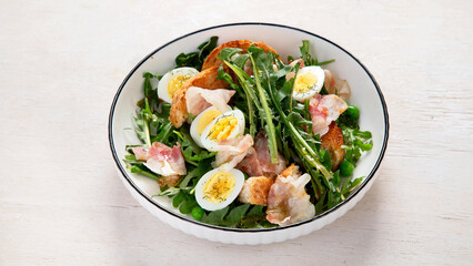 Summer fresh salad from dandelion leaves, eggs, bacon and with bread on light background