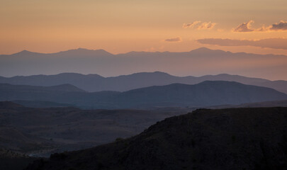 Majestic Sunset. A Layered Landscape of Mountain Hills Bathed in Orange Hues. Somewhere in...