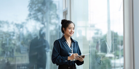 happy professional business woman working on tablet at work standing near window