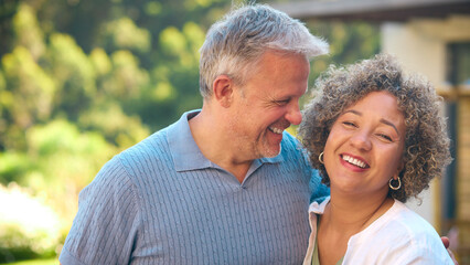 Portrait Of Laughing And Smiling Mature Multi-Racial Couple Standing Outdoors In Countryside