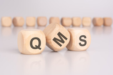 text 'QMS' - Quality Management System - on wooden cubes