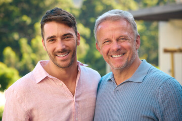 Portrait Of Laughing And Smiling Mature Father With Adult Son Standing Outdoors In Countryside
