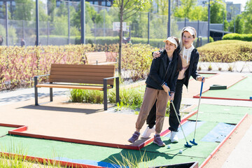 mother and daughter playing mini golf, children enjoying summer vacation - 792735183