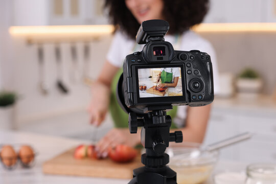 Food blogger cooking while recording video in kitchen, focus on camera
