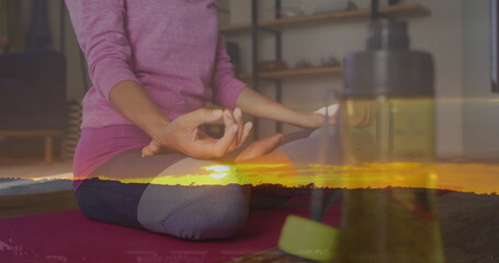 Image of sunset landscape over woman practicing yoga, exercising at home