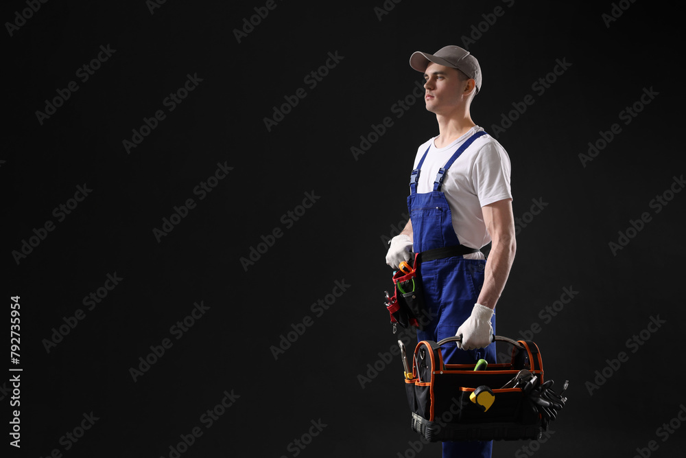 Wall mural professional repairman with tool box on black background. space for text