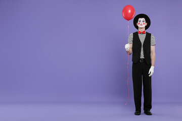 Funny mime artist with balloon on purple background. Space for text