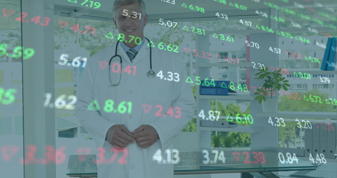 Image of stock market data processing over caucasian male doctor smiling at hospital