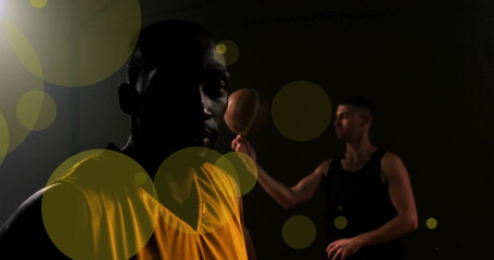 Image of diverse basketball players with ball and spots of light on black background