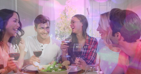 Image of bokeh over happy caucasian female and male friends drinking wine and talking - obrazy, fototapety, plakaty