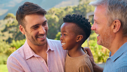Portrait Of Three Generation Male Family Laughing And Smiling Standing Outdoors In Countryside