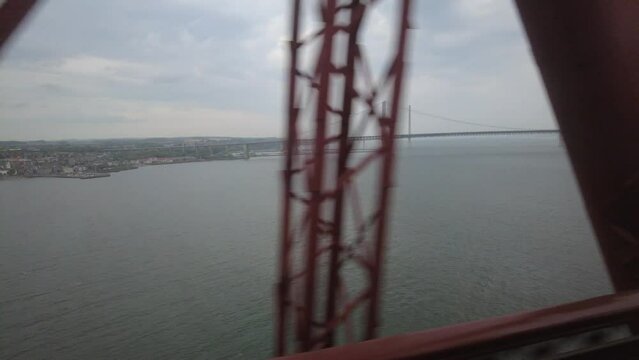 Train crossing historic forth rail bridge with view of the forth road bridges