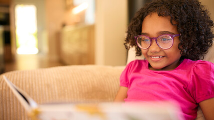 Girl Wearing Glasses At Home Sitting On Sofa Reading A Story Together