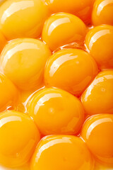 Close-up of several large yolks. The eggs are arranged in a way that creates a sense of depth and...