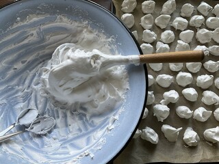Whipped eggs with sugar for Meringue cookies on baking tray with baking paper and metal bowl with...