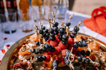 Valmiera, Latvia - August 10, 2023 - Gourmet appetizers on a gold tray with skewered berries,...