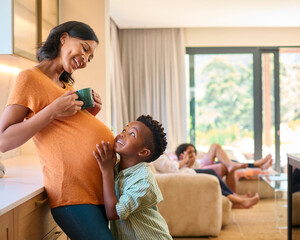 Multi Generation Family At Home With Son Listening To Baby's Heartbeat In Pregnant Mother's Tummy