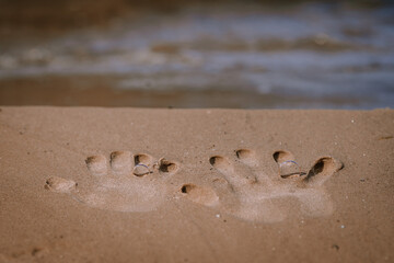 Valmiera, Latvia - August 10, 2023 - Handprints and wedding rings in the sand on a beach.