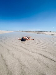 Young Girl laying in tide pool  at Low Tide on Cape Cod beach