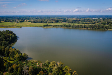 Valmiera, Latvia - August 10, 2023 - Aerial view of a large lake surrounded by forests and fields on a clear day.