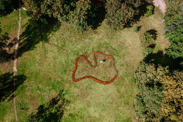 Valmiera, Latvia - August 10, 2023 - Aerial view of a heart-shaped floral arrangement on grass,...