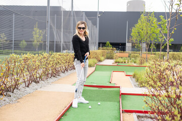 Playing Adventure Golf, downhill shot, ball, club and hole.