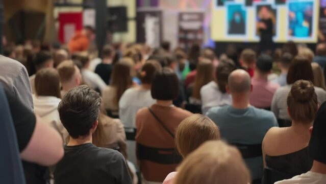 Energetic young adults observe a startup pitch, speaker in defocus at a business seminar. Aspiring entrepreneurs gather for insights. Depicts the vibrancy of youth in business incubation forums