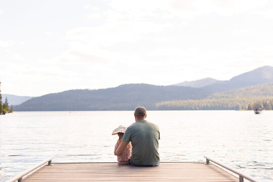 Dad and daughter sitting on dock at lake - Powered by Adobe