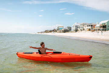 Boy in kayak by beach homes on a sunny day
