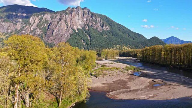 Scenic drone view flying over Snoqualmie Middle Fork River with Mount Si in the background during a blue sky day in North Bend, Washington State. Landscapes and rivers of Pacific Northwest