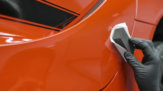 Application Of Ceramic Coating On The Red Car Using Suede Cloth On The Applicator Sponge. - closeup shot