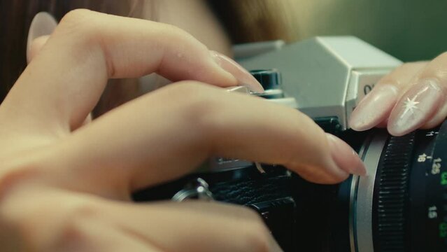 close up of female hand with long nails pressing the shutter button on old vintage retro camera film 