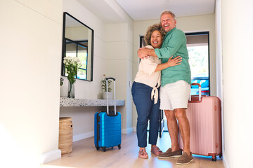 Excited Multi Racial Mature Couple With Luggage Arriving In House Or Apartment For Summer Vacation