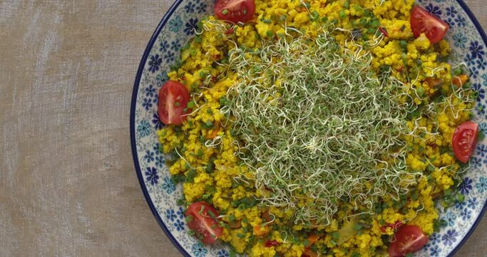 Millet and Vegetable Stir-Fry, decorated with quartered tomatoes and topped with chopped chives and alfalfa sprouts.  Space for text, table spin. 