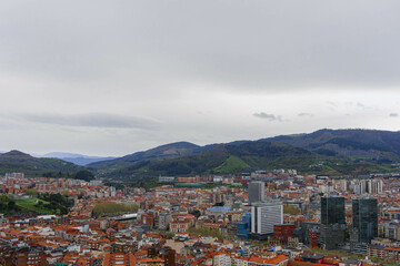 Naklejka premium panorama of the city of bilbao with cloudy sky and mountains with modern big business tower