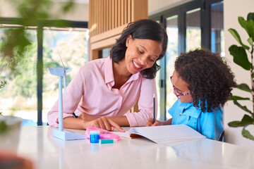 Family With Mother And Daughter Doing Homework On Green Energy With Model Turbine