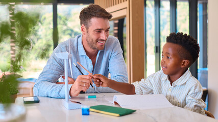 Multi Racial Family With Father And Son Doing Homework On Green Energy With Model Turbine