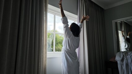 Person Reaching Up to Curtain in Room