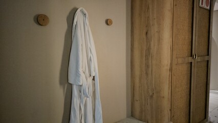 White Robe Hanging Beside Wooden Cabinet