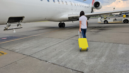 Man Walking Towards Airplane With Yellow Suitcase