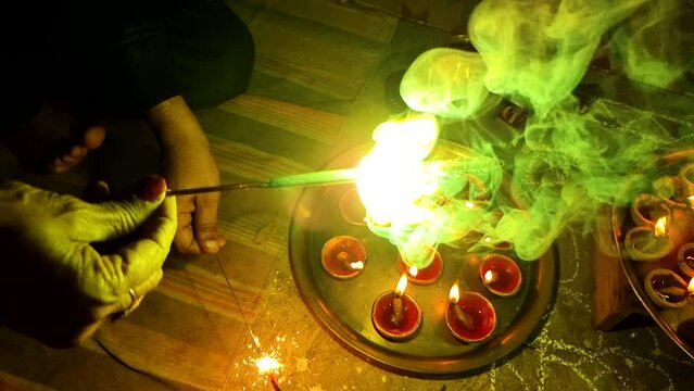 Super slow motion shot showing Phuljadhi, sparklers giving smoke and pollution with earthenware oil filled lamps in the background showing the celebration of diwali dussera hindu festival of light